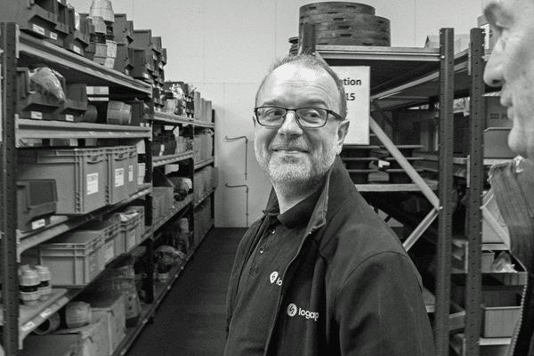 Man smiling in warehouse aisle with shelves